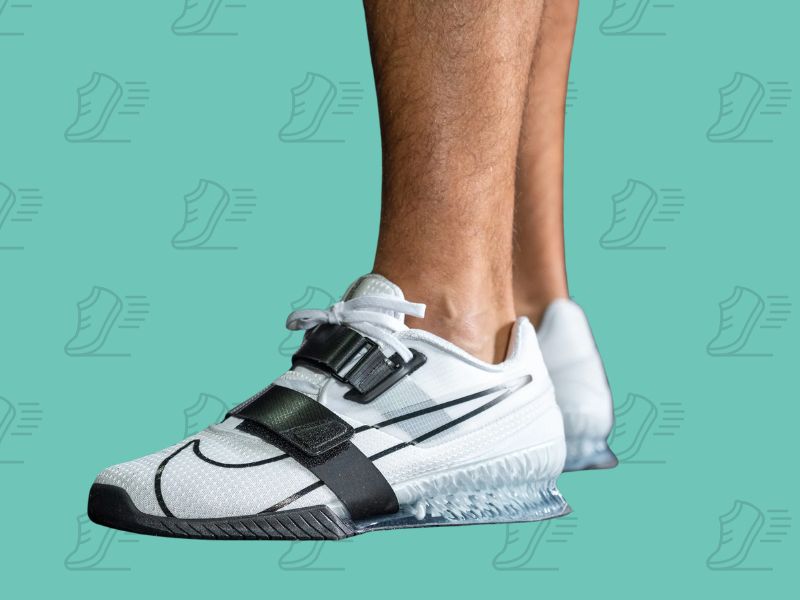 Muška noga u belim Nike Romaleos 4 patikama sa dvostrukim kaiševima – obuća za maksimalnu stabilnost pri dizanju tegova