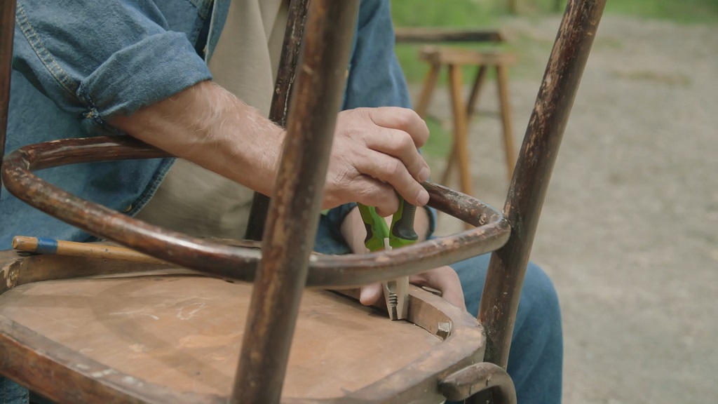 Muškarac popravlja svoju staru stolicu