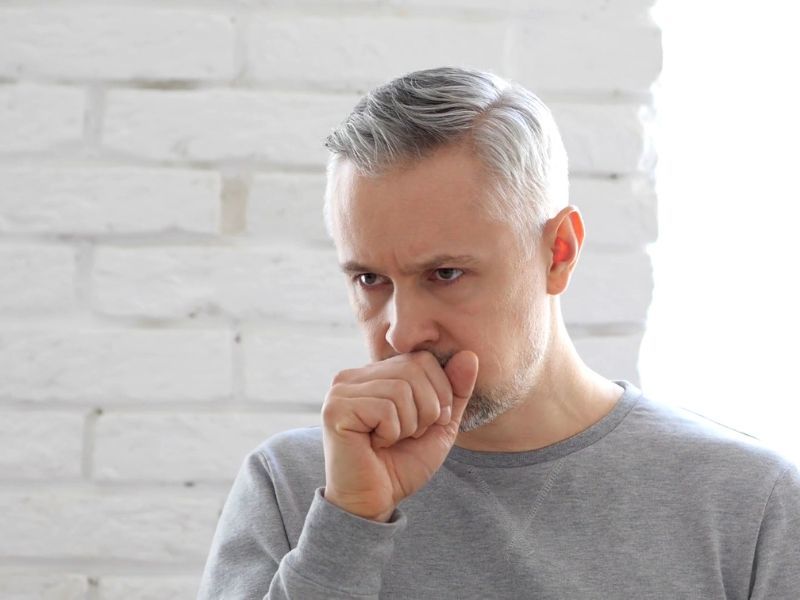 prikaz muškarca srednjih godina koji kašlje i drži ruku na ustima