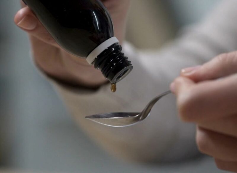 ženska osoba sipa sirup za suvi kašalj u kašičicu