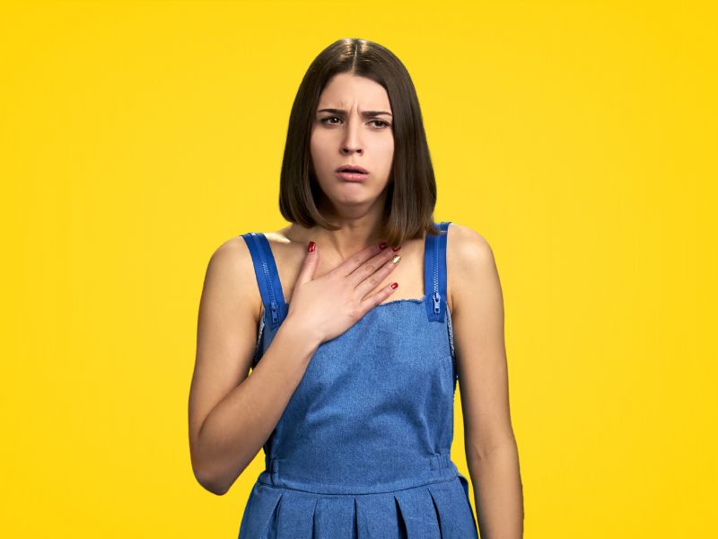 devojka se drži za pluća i kašlje, žuta pozadina