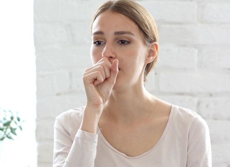 devojka drži ruku preko usana i kašlje