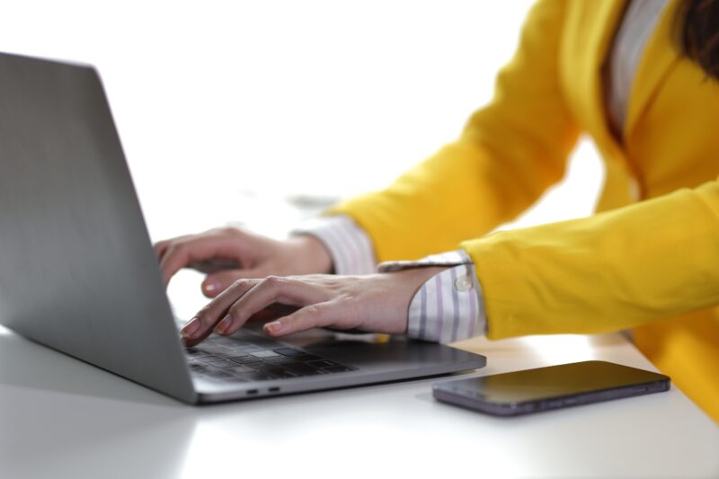 devojka u žutom sakou koristi laptop