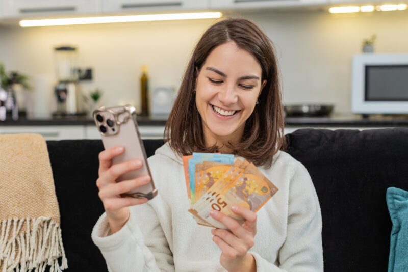 Žena drži papirni novac i telefon, simbolika novca u snovima prema narodnim tumačenjima